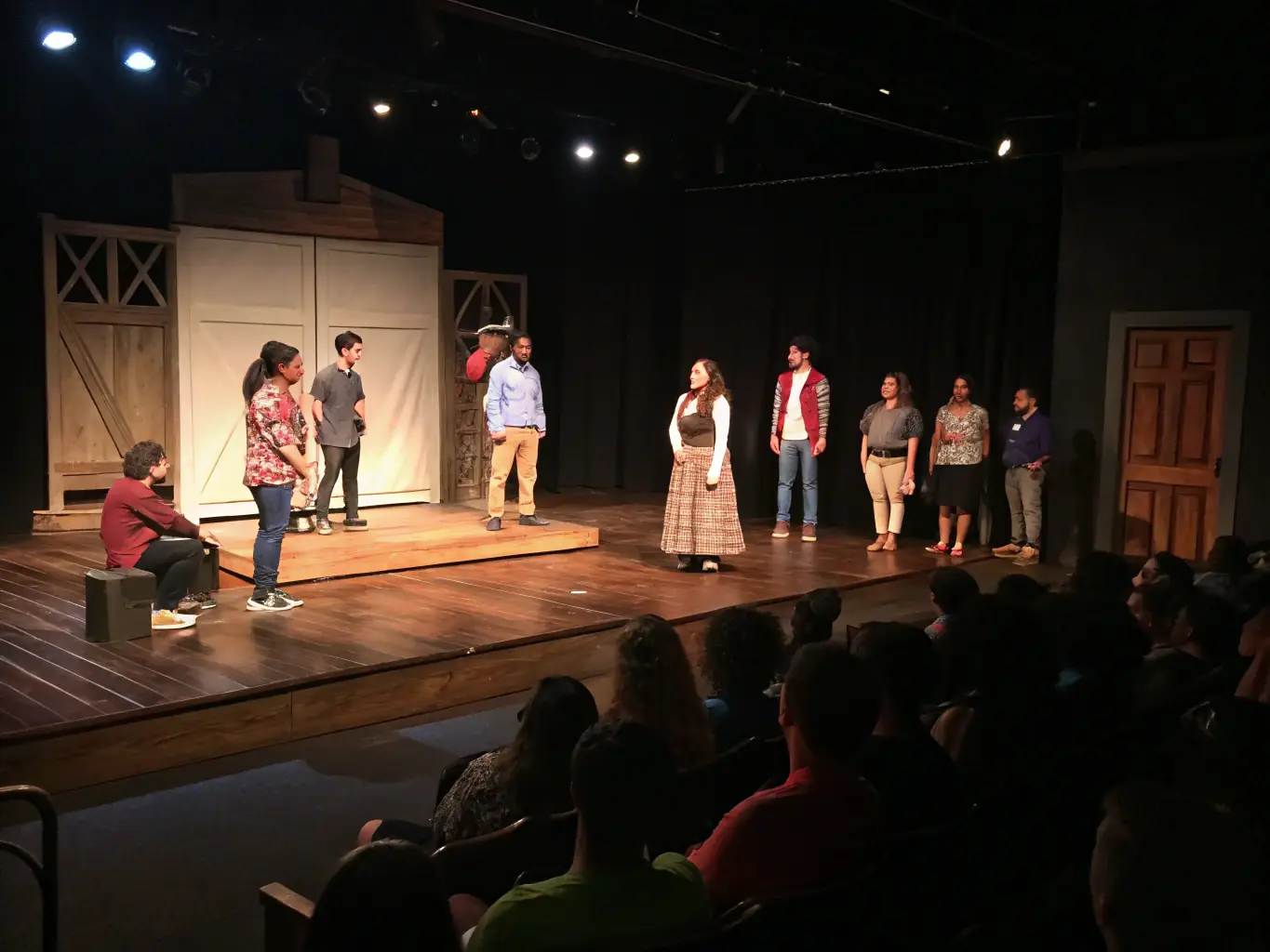 A vibrant image depicting a community theater performance organized by ASSOC LES SOUFFLEURS DE REVES, showcasing actors on stage with a diverse audience enjoying the show.